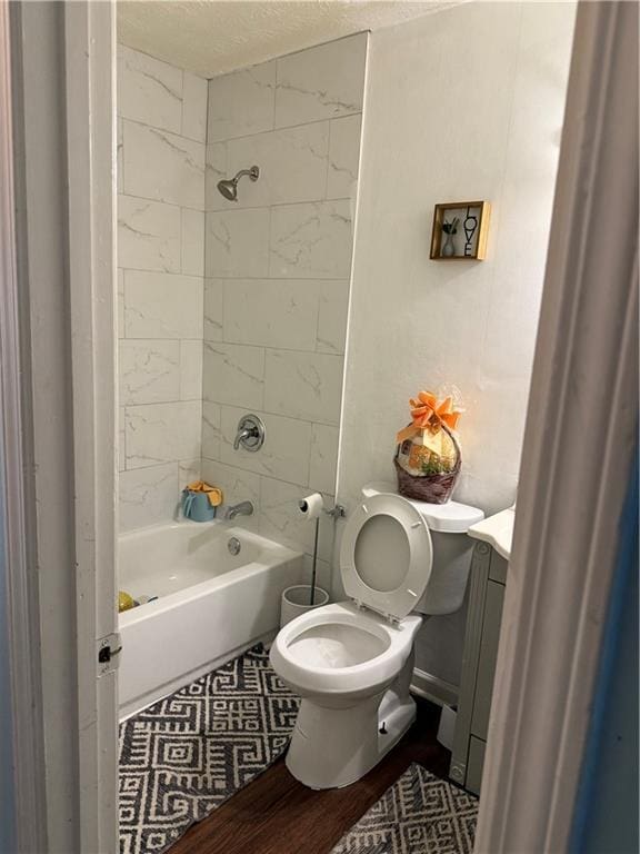 full bathroom featuring hardwood / wood-style flooring, tiled shower / bath combo, vanity, a textured ceiling, and toilet