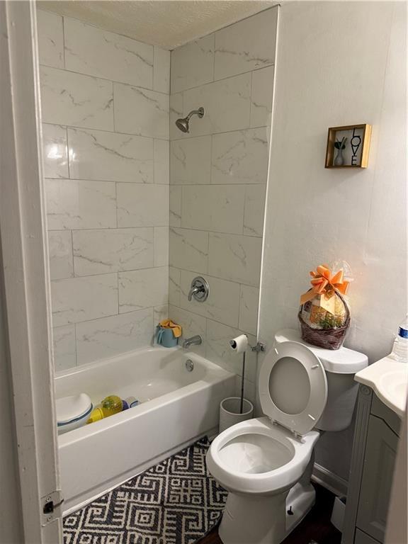 full bathroom with tiled shower / bath combo, vanity, tile patterned floors, and toilet