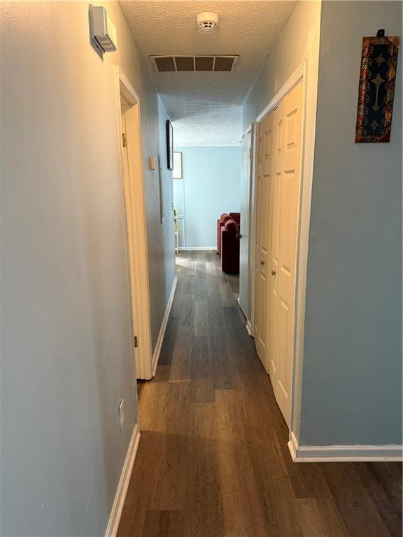 hall featuring dark wood-type flooring and a textured ceiling