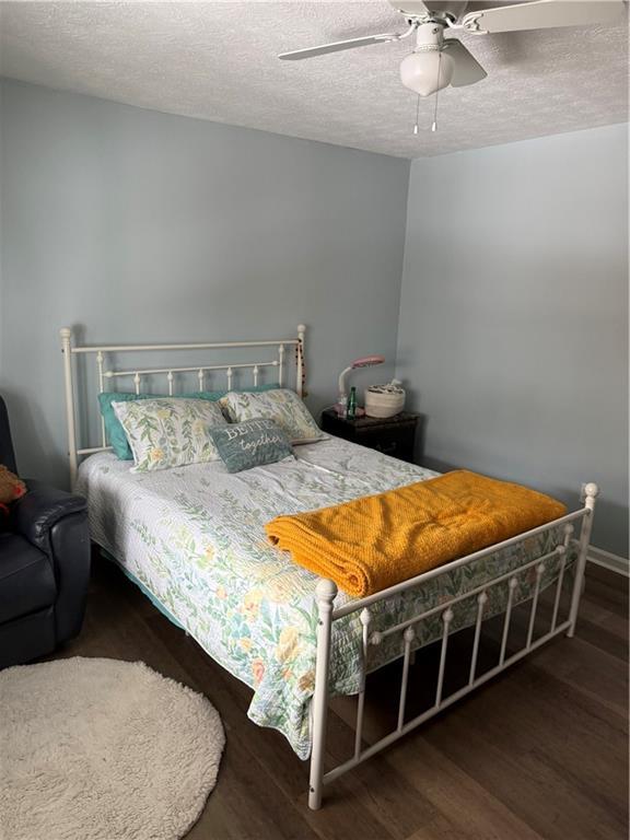 bedroom featuring a textured ceiling, dark hardwood / wood-style floors, and ceiling fan