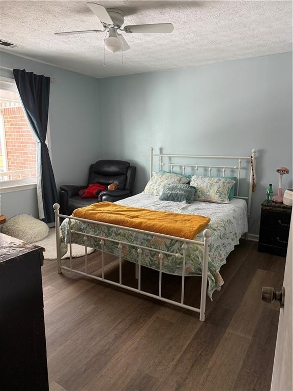 bedroom with ceiling fan, dark hardwood / wood-style flooring, and a textured ceiling