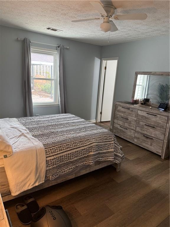 bedroom featuring a textured ceiling, dark wood-type flooring, and ceiling fan