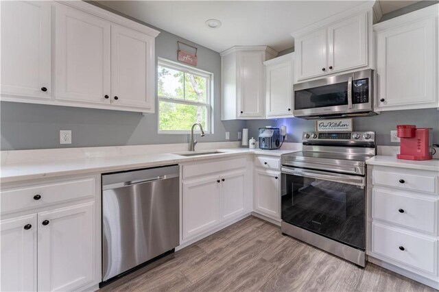 250 Silas Rd, Dahlonega, GA 30533 - kitchen featuring stainless steel appliances, a sink, white cabinetry, light countertops, and light wood-style flooring