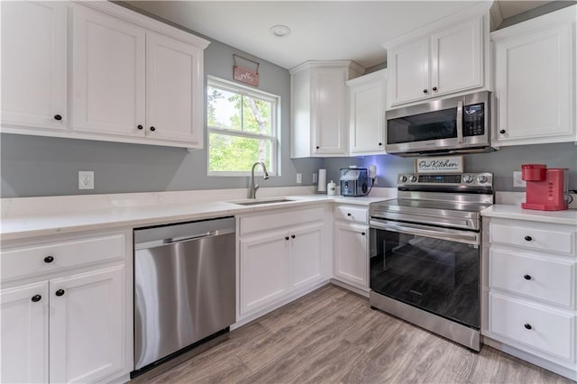 250 Silas Rd, Dahlonega, GA 30533 - kitchen featuring stainless steel appliances, a sink, white cabinets, light countertops, and light wood-type flooring