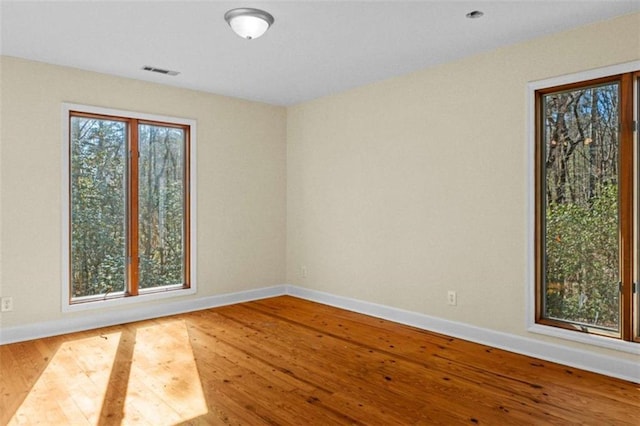 unfurnished room featuring visible vents, baseboards, and wood finished floors