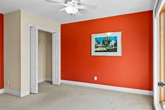 unfurnished bedroom with a closet, light colored carpet, ceiling fan, and baseboards