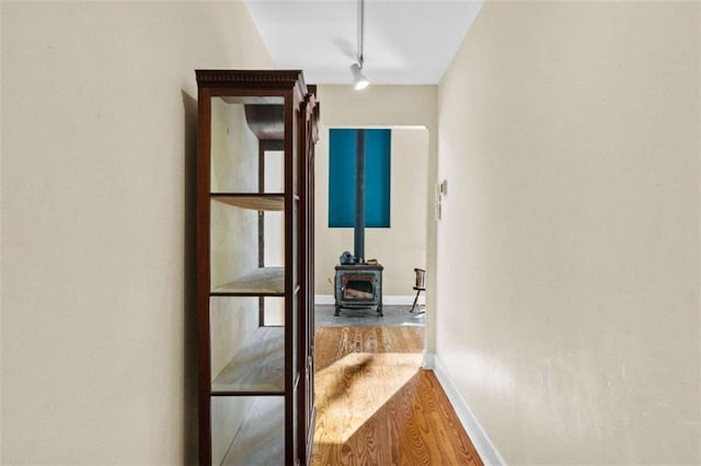 hall with baseboards, wood finished floors, and track lighting