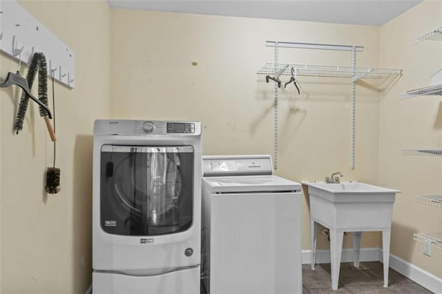 clothes washing area with laundry area, washing machine and dryer, and baseboards