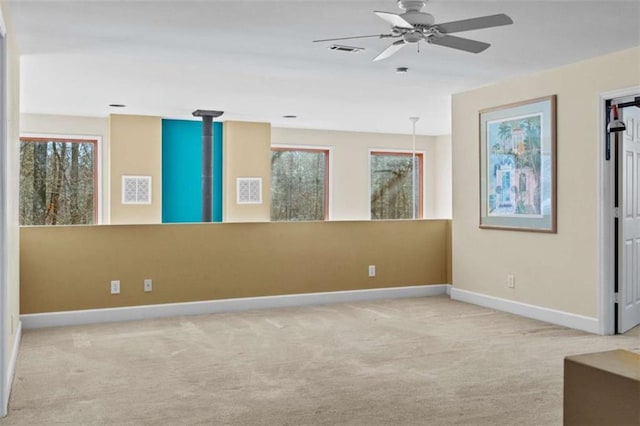 spare room with light carpet, baseboards, visible vents, and a ceiling fan