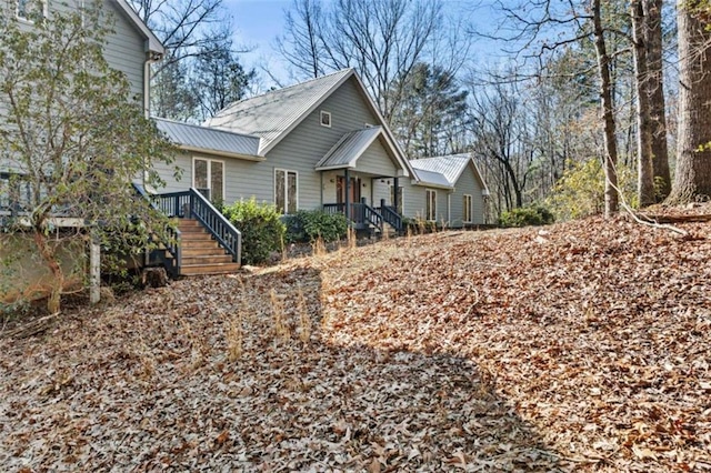 view of front of property featuring stairway and metal roof