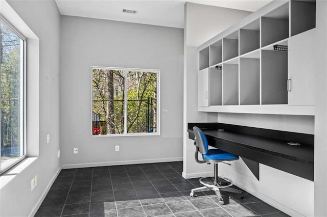 office space with built in desk, dark tile patterned floors, and baseboards