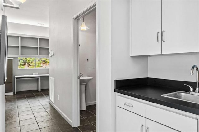 kitchen featuring dark countertops, white cabinets, a sink, and dark tile patterned flooring