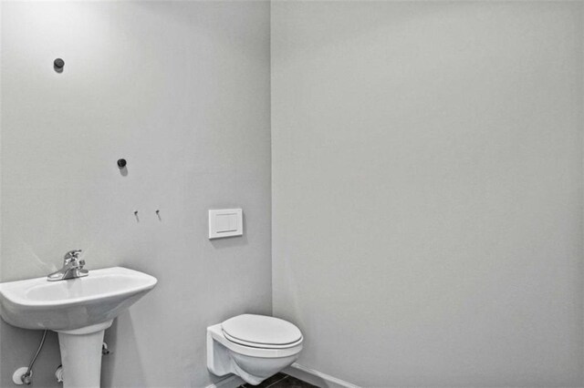 bathroom featuring toilet, baseboards, and a sink