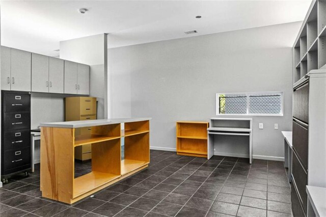 kitchen featuring baseboards, visible vents, a peninsula, light countertops, and dark tile patterned floors