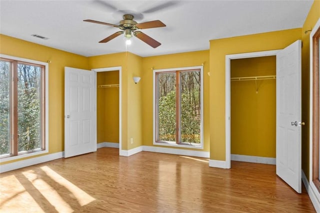 unfurnished bedroom featuring visible vents, light wood-style flooring, and multiple windows