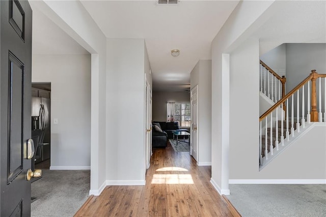 foyer entrance featuring stairway, wood finished floors, visible vents, and baseboards