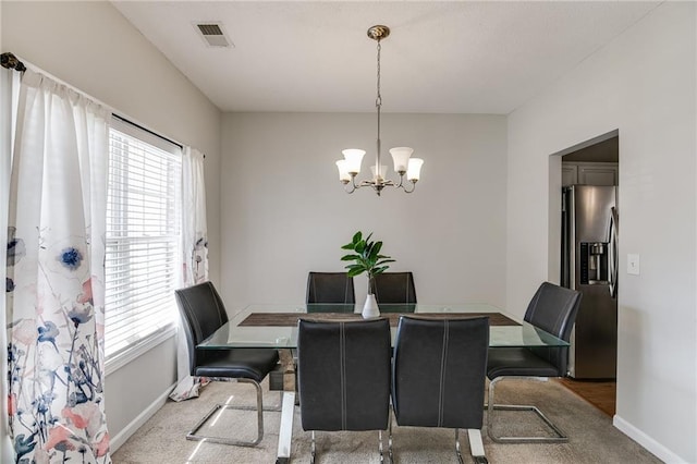 dining area with a wealth of natural light, carpet flooring, visible vents, and a notable chandelier