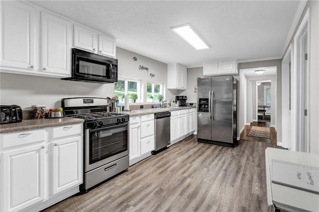 4481 Mclain Cir, Acworth, GA 30101 - kitchen featuring light wood-style flooring, a sink, a textured ceiling, stainless steel appliances, and white cabinets