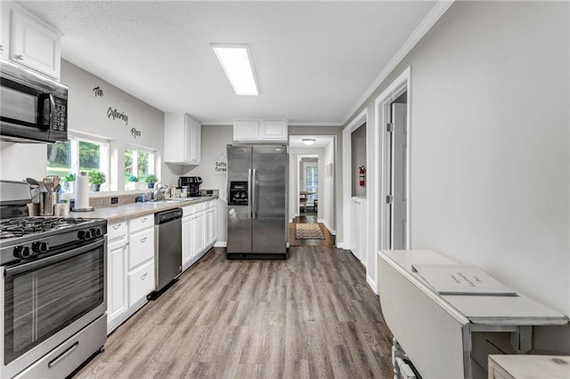 4481 Mclain Cir, Acworth, GA 30101 - kitchen featuring light countertops, light wood-style floors, white cabinets, stainless steel appliances, and a sink