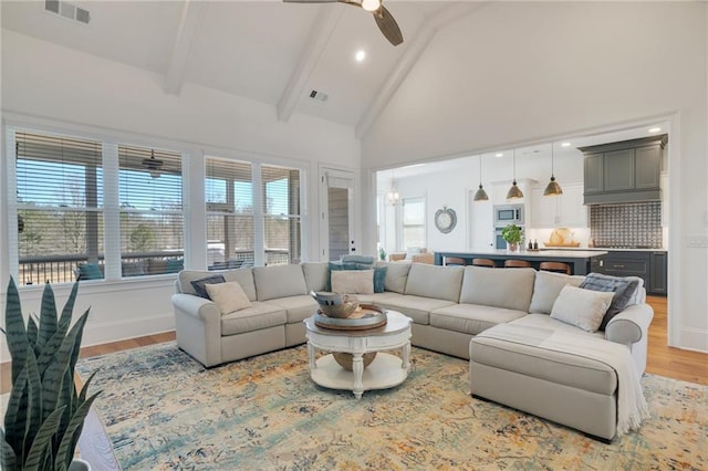 living room with beam ceiling, a ceiling fan, visible vents, and high vaulted ceiling