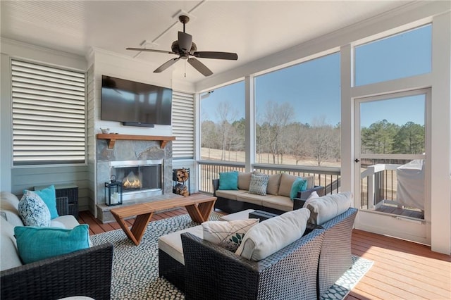 sunroom / solarium with an outdoor living space with a fireplace, a healthy amount of sunlight, and ceiling fan