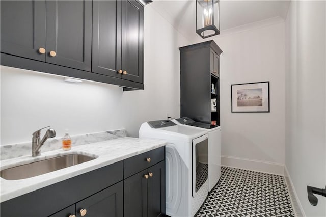 clothes washing area with baseboards, cabinet space, a sink, washer and dryer, and crown molding