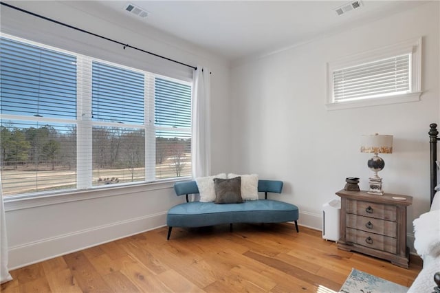 living area featuring baseboards, visible vents, and light wood finished floors