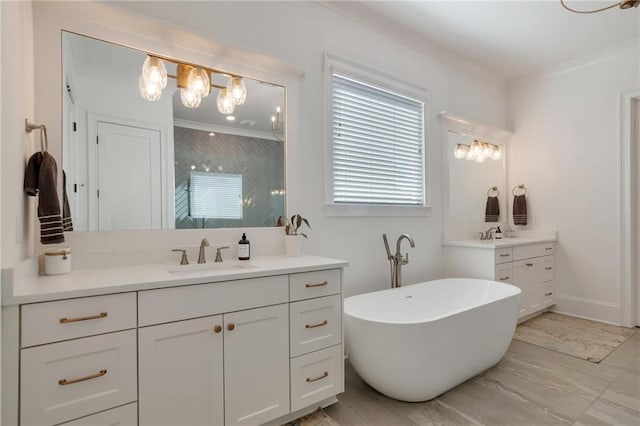 bathroom with a notable chandelier, two vanities, ornamental molding, a sink, and a freestanding bath