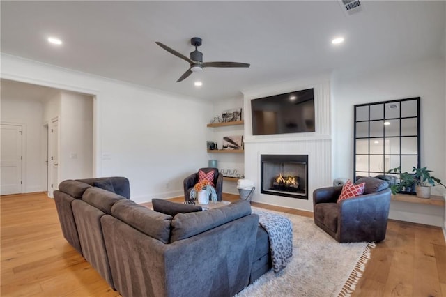 living room featuring recessed lighting, light wood-style floors, a fireplace, and a ceiling fan