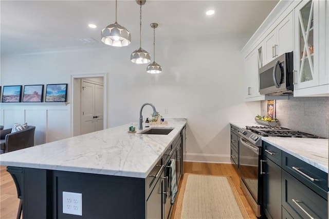 kitchen with a sink, tasteful backsplash, white cabinetry, appliances with stainless steel finishes, and a peninsula