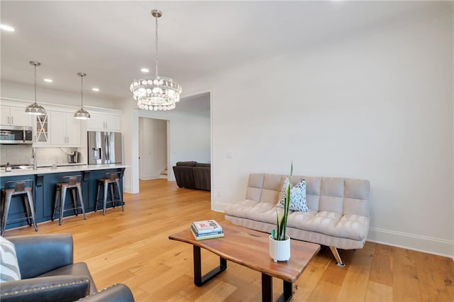 living room featuring an inviting chandelier, light wood-style flooring, recessed lighting, and baseboards