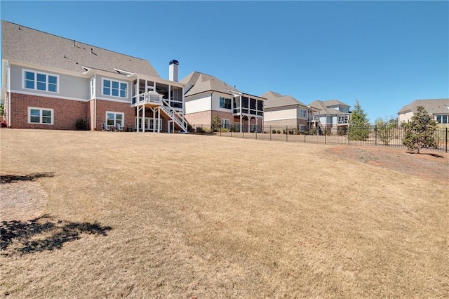 view of yard featuring stairway, a residential view, fence, and a sunroom