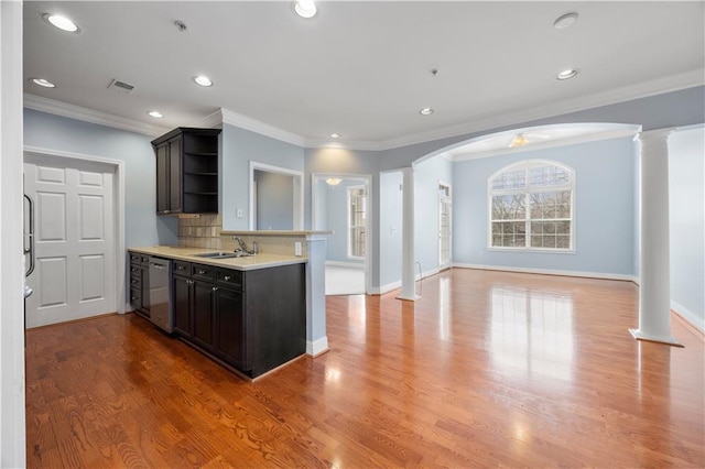 kitchen featuring light countertops, stainless steel dishwasher, decorative backsplash, open shelves, and decorative columns