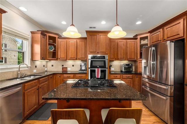 11271 Calypso Dr, Alpharetta, GA 30009 - kitchen with appliances with stainless steel finishes, brown cabinetry, light wood-style floors, a kitchen island, and recessed lighting