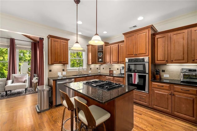 11271 Calypso Dr, Alpharetta, GA 30009 - kitchen featuring stainless steel appliances, brown cabinets, light wood finished floors, and ornamental molding