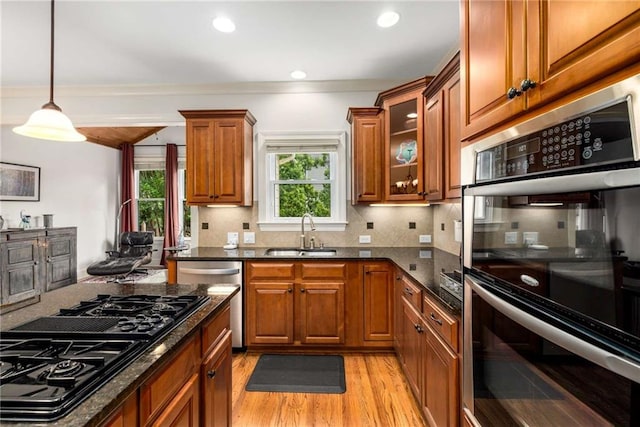 11271 Calypso Dr, Alpharetta, GA 30009 - kitchen with appliances with stainless steel finishes, brown cabinets, light wood-style flooring, dark stone counters, and recessed lighting