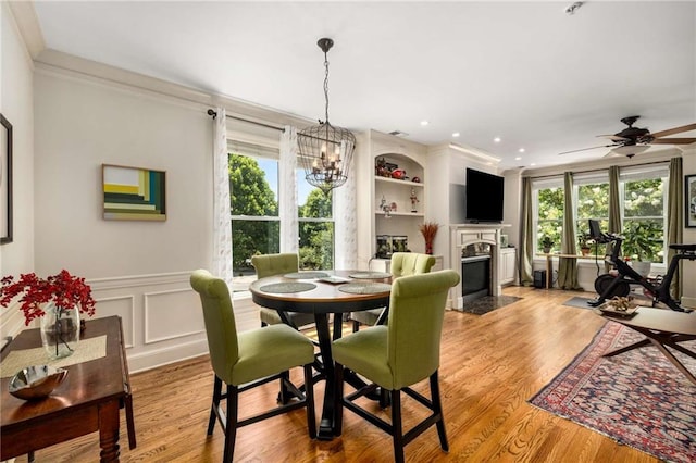 11271 Calypso Dr, Alpharetta, GA 30009 - dining space featuring a fireplace with flush hearth, a chandelier, wainscoting, ceiling fan, and wood finished floors