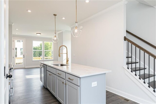 kitchen featuring decorative light fixtures, a sink, stainless steel dishwasher, light stone countertops, and a center island with sink