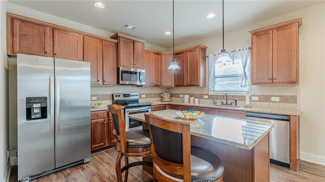 879 Tranquil Way, Hampton, GA 30228 - kitchen featuring appliances with stainless steel finishes, light wood-style floors, backsplash, a center island, and light stone countertops