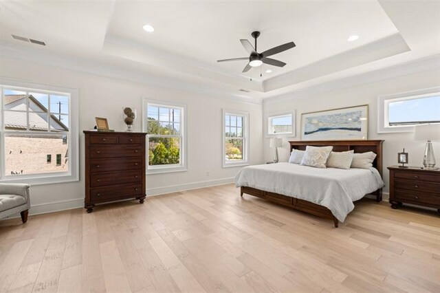 bedroom with a tray ceiling, ceiling fan, ornamental molding, and light wood-type flooring