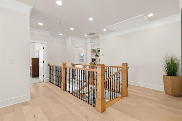 hallway featuring built in shelves, crown molding, and light hardwood / wood-style floors