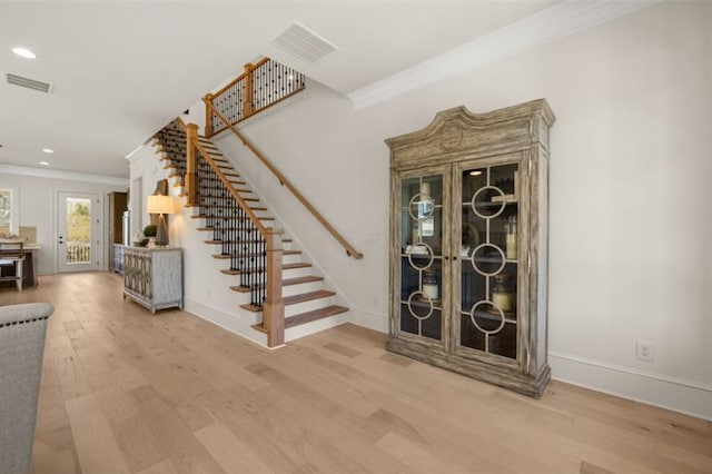 stairs featuring wood-type flooring and ornamental molding