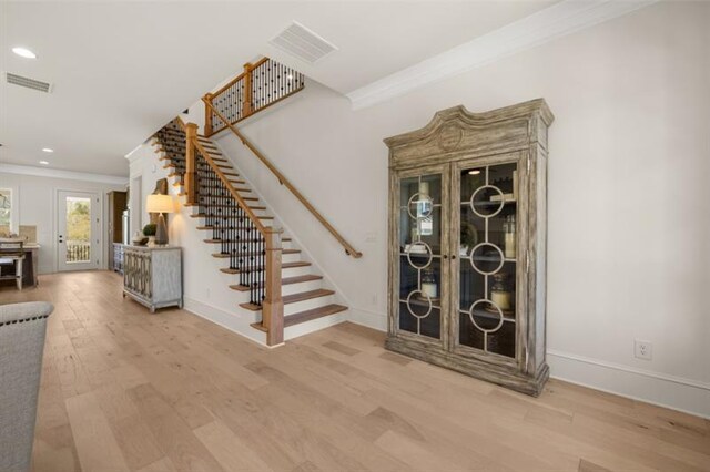 dining space with light wood-type flooring, built in features, and ornamental molding