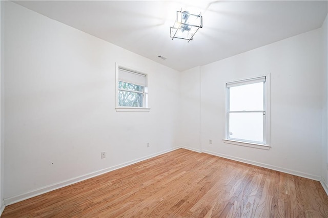 spare room featuring baseboards and light wood finished floors