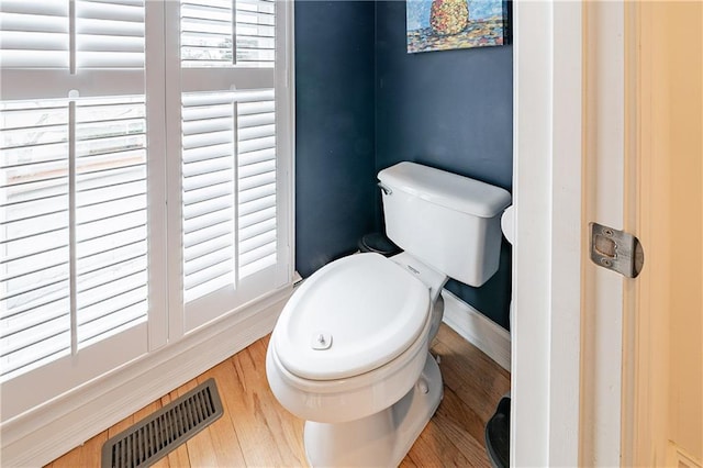 bathroom featuring toilet, baseboards, visible vents, and wood finished floors