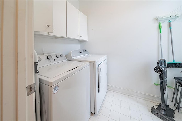 clothes washing area with cabinet space, light tile patterned floors, baseboards, and washer and clothes dryer