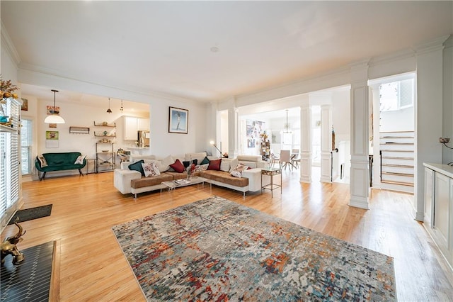 living area with ornamental molding, stairway, light wood-type flooring, and decorative columns