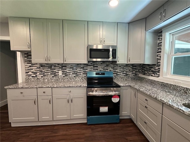 6538 N Sweetwater Rd, Lithia Springs, GA 30122 - kitchen featuring appliances with stainless steel finishes, dark wood finished floors, decorative backsplash, and light stone countertops