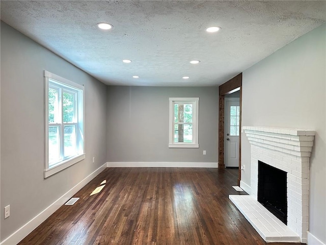 6538 N Sweetwater Rd, Lithia Springs, GA 30122 - unfurnished living room featuring dark wood finished floors, baseboards, a textured ceiling, a fireplace, and recessed lighting
