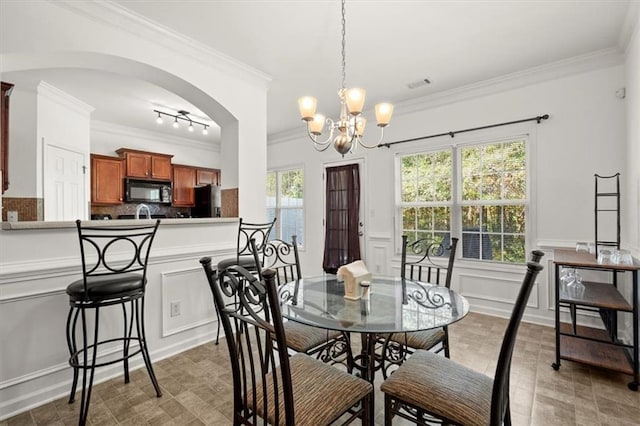 dining space with ornamental molding and a notable chandelier